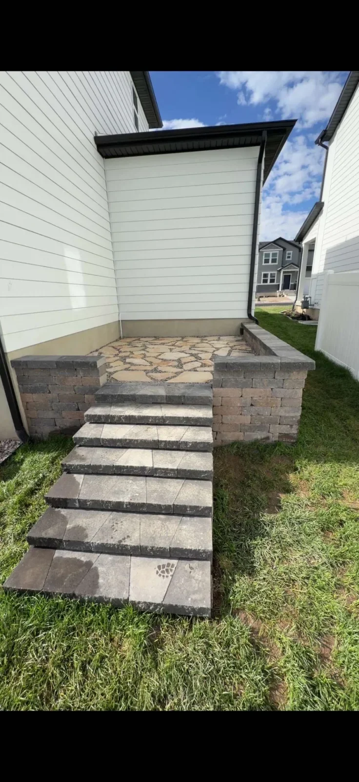 Completed client paver steps leading to a flagstone patio