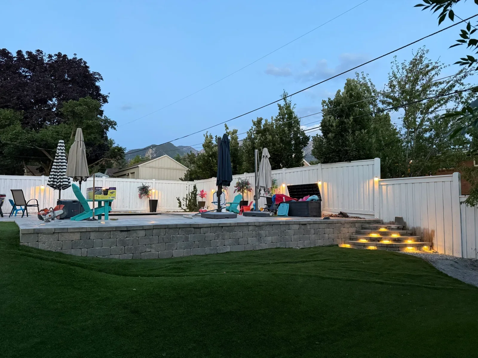 Completed client lawn, retaining wall, and illuminated patio steps at blue hour