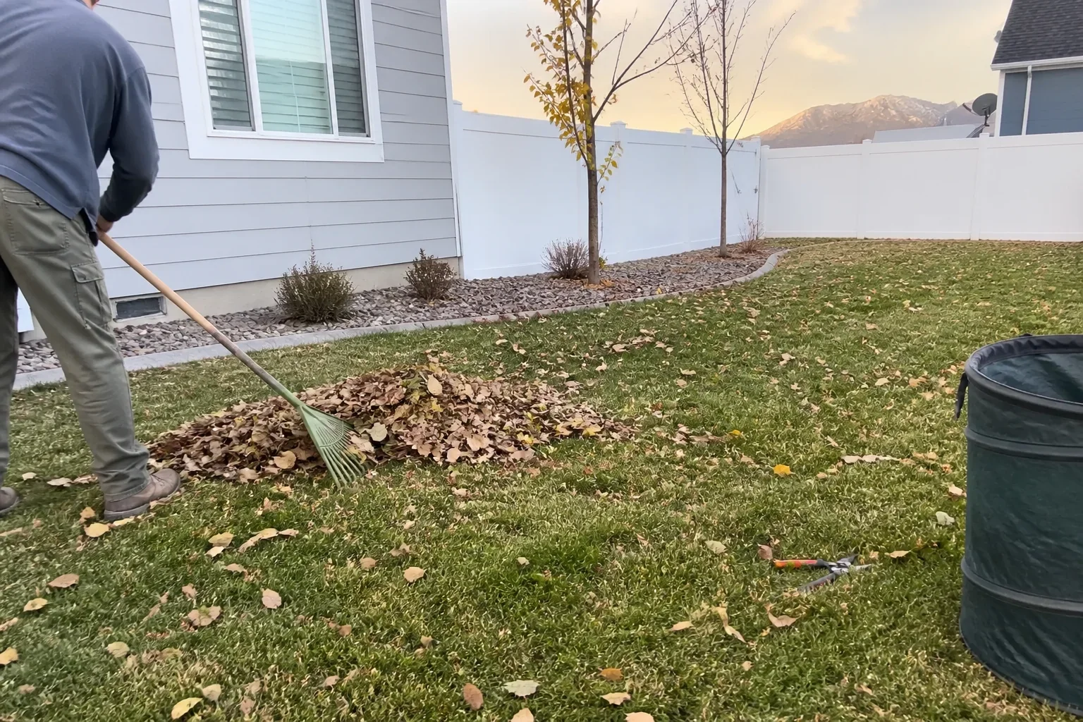 Landscaper raking autumn leaves during a seasonal cleanup at a Utah home